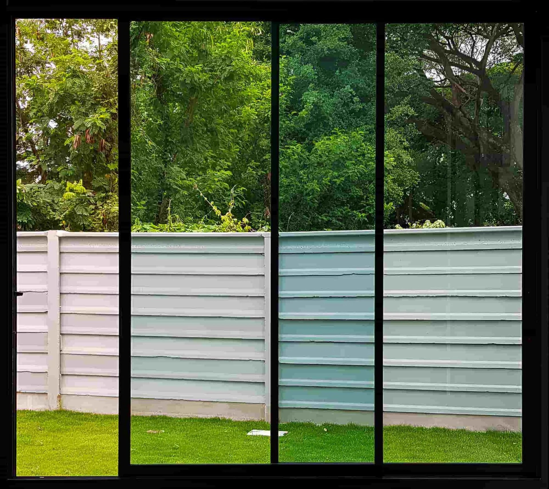 Black-framed sliding glass doors looking out over a backyard fence and garden